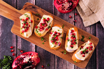 Holiday crostini appetizers with brie cheese, pomegranates and parsley. Above view on a serving...