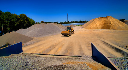 Sand quarry, excavating equipment, bulldozer with heap of sand and gravel in background. Selective...