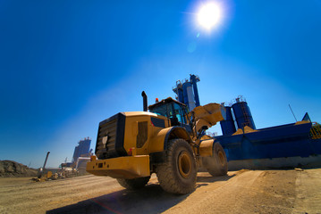 Fototapeta premium Large tracked excavator on a construction site. Road repair, asphalt replacement. Loading of stone and rubble for its processing at a concrete factory.