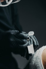 The blackbrow microblading master in black rubber picks up the paint for maniple for further drawing the eyebrows along the ready-made contour drawn in advance on the face of the model.