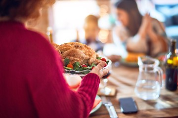 Beautiful family smiling happy and confident. One of them standing showing roasted turkey celebrating thanksgiving day at home