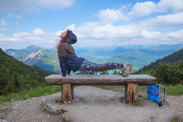 young woman doing sports on a wooden bench in the bavarian alps