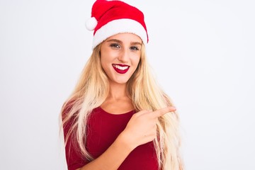 Young beautiful woman wearing Christmas Santa hat over isolated white background cheerful with a smile of face pointing with hand and finger up to the side with happy and natural expression on face