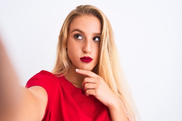 Young beautiful woman wearing t-shirt make selfie by camera over isolated white background serious face thinking about question, very confused idea