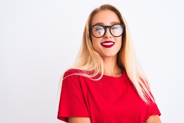 Young beautiful woman wearing red t-shirt and glasses standing over isolated white background happy face smiling with crossed arms looking at the camera. Positive person.