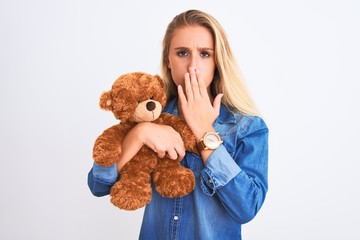 Young beautiful woman holding cute teddy bear standing over isolated white background cover mouth with hand shocked with shame for mistake, expression of fear, scared in silence, secret concept