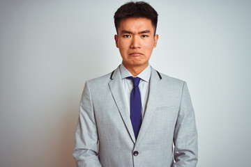 Asian chinese businessman wearing grey jacket and tie standing over isolated white background depressed and worry for distress, crying angry and afraid. Sad expression.