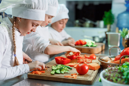 Children grind vegetables in the kitchen.