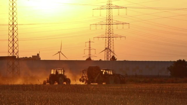 Sonnenuntergang mit Strommasten und Windkraftr&auml;dern und Traktore