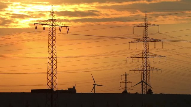 Sonnenuntergang mit Strommasten und Windkraftr&auml;dern