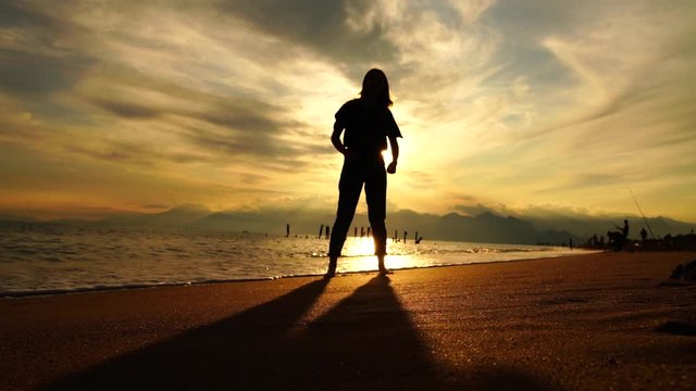 silhouette of a girl jumping on the beach at sunsent