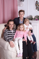 family in a chair by the fireplace in the Christmas decorations