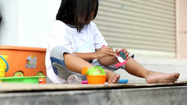 Asian children sit on the floor for playing kitchen toy 