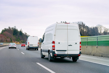 Fototapeta na wymiar White Minivans in road. Mini van auto vehicle on driveway. European van transport logistics transportation. Auto with driver on highway.