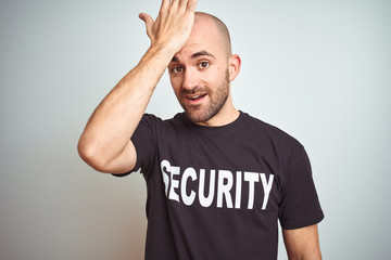 Young safeguard man wearing security uniform over isolated background surprised with hand on head for mistake, remember error. Forgot, bad memory concept.