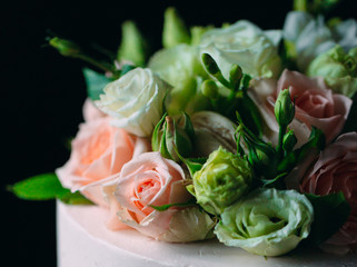 Cake is decorated with flowers on a dark background.