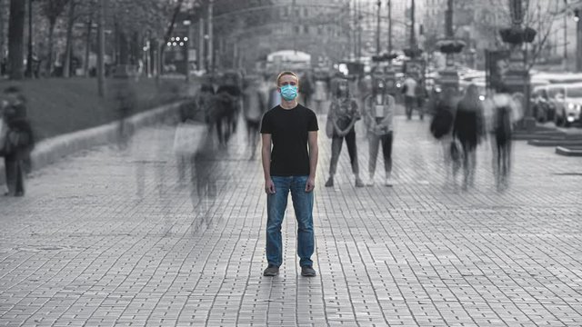The man with medical face mask stands in the crowded city. time lapse