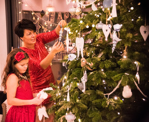 Dekorowanie domu na święta Bożego Narodzenia, ubieranie choinki, mama z córką stroją choinkę na Boże Narodzenie - obrazy, fototapety, plakaty