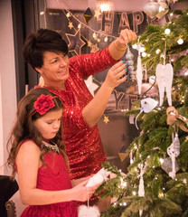Mama z córką dekorują choinkę na święta Bożego Narodzenia - obrazy, fototapety, plakaty