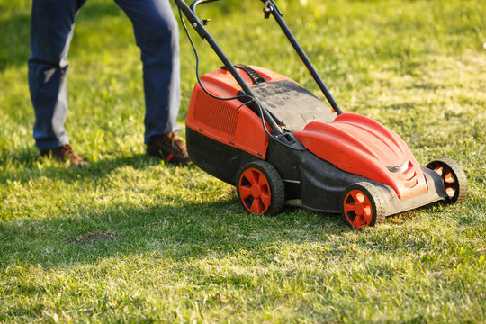 mowing trimmer - worker cutting grass in green yard at sunset. Man with  electric lawnmower, lawn mowing. Gardener trimming a garden. Stock Photo |  Adobe Stock