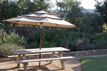 A wooden picnic table with an umbrella in the California wine country on a warm autumn day
