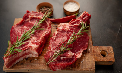 Fresh beef steak with herbs and salt on a stone background