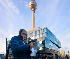 Young man reading tourist city map on hoiliday in Berlin, Germany, in winter.