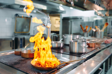 Modern kitchen. Cooks prepare meals on the stove in the kitchen of the restaurant or hotel. The fire in the kitchen.