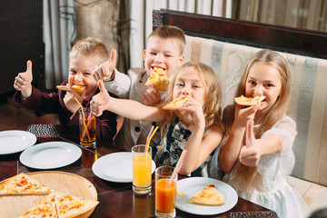 Children eat pizza in the restaurant.