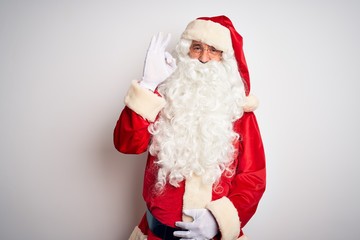 Middle age handsome man wearing Santa costume standing over isolated white background smiling positive doing ok sign with hand and fingers. Successful expression.
