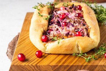 Homemade open pie with different types of cabbage, sauerkraut and cranberry on wooden cutting board. Selective focus. Vegetarian food.