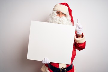 Middle age man wearing Santa Claus costume holding banner over isolated white background surprised with an idea or question pointing finger with happy face, number one