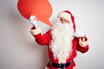 Middle age man wearing Santa costume holding speech bubble over isolated white background with surprise face pointing finger to himself