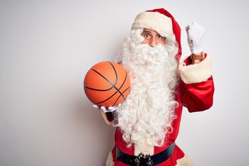 Senior man wearing Santa Claus costume holding basketball ball over isolated white background annoyed and frustrated shouting with anger, crazy and yelling with raised hand, anger concept