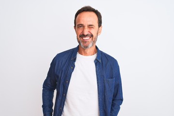 Fototapeta premium Middle age handsome man wearing blue denim shirt standing over isolated white background winking looking at the camera with sexy expression, cheerful and happy face.