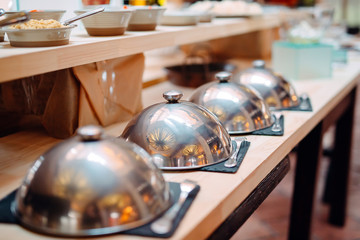 buffet in a restaurant or hotel. Metal dishes with caps.