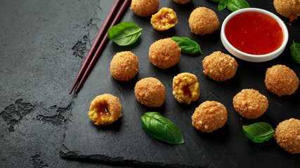 Fried Rice Balls with sweet hot sauce and wooden chopstick on rustic stone board