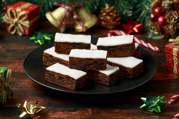Christmas iced fruit cake with decoration, gifts, green tree branch on wooden rustic table