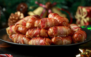 Christmas Pigs in blankets, sausages wrapped in bacon with decoration, gifts, green tree branch on...
