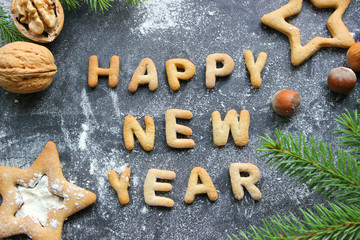 Baked letters Happy New year, stars, snowflakes.Greeting card with gingerbread.Christmas card made of gingerbread on a wooden table surrounded by fir branches, nuts, spices and orange. Rustic style, c