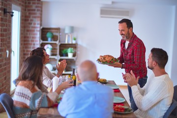 Beautiful family smiling happy and confident. Showing roasted turkey and applauding celebrating Thanksgiving Day at home