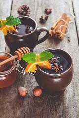 Hot mulled wine with orange, cinnamon, honey and anise on wooden background.