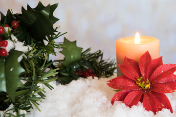 Red Poinsettia flower with lit candle and Mistletoe in snow. White Christmas Background with...