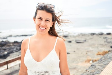 Beautiful young woman walking on beach promenade enjoying ocean view smiling happy on summer vacation