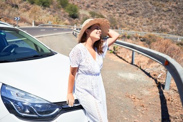 Young beautiful tourist woman smiling happy by the car enjoying summer vacation on a road trip