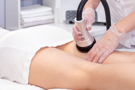 Cosmetologist reducing cellulite on hips of  female patient, using ultrasound cavitation machine. Cropped shot of a woman getting rf lifting treatment on back of her legs by professional beautician.