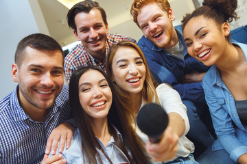 Group of friends having party indoors fun together giving mike