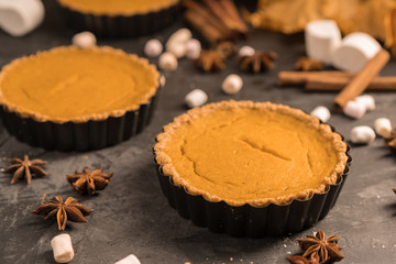 Yellow pumpkin pie orange  pumpkins with yelllow dry autumn leaves decor on dark table background.Harvesting,autumn and Thanksgiving concept