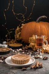 Yellow pumpkin pie orange  pumpkins with yelllow dry autumn leaves decor on dark table background.Harvesting,autumn and Thanksgiving concept