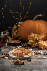 Yellow pumpkin pie orange  pumpkins with yelllow dry autumn leaves decor on dark table background.Harvesting,autumn and Thanksgiving concept